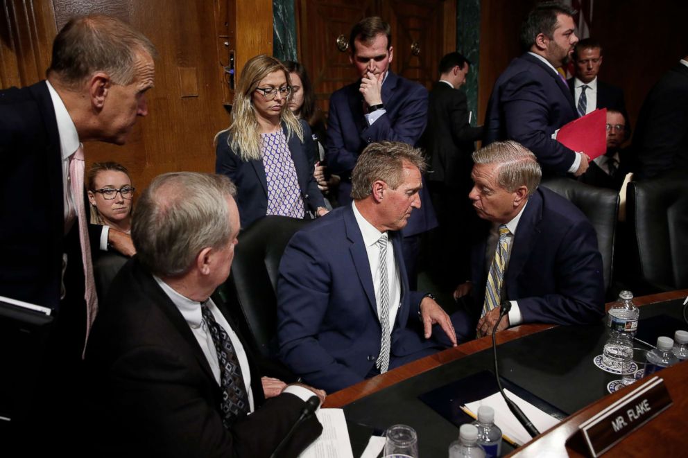 PHOTO: Republican members of the Senate Judiciary Committee and staff surround Sen. Jeff Flake, center, at the end of the Kavanaugh confirmation hearings, Sept. 28, 2019. From left to right are Sen. Thom Tillis,Sen. Mike Crapo, and Sen. Lindsey Graham. 