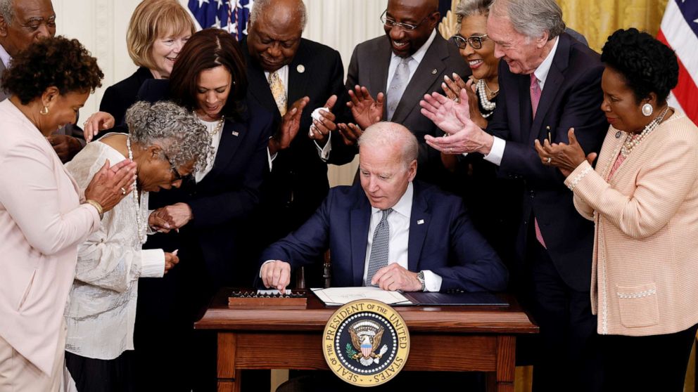PHOTO: President Joe Biden is applauded as he reaches for a pen to sign the Juneteenth National Independence Day Act into law as Vice President Kamala Harris stands by in the East Room of the White House June 17, 2021. 
