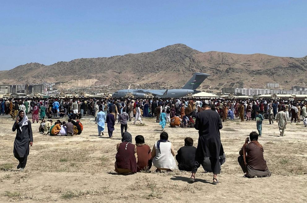 PHOTO: Hundreds of people gather near a U.S. Air Force C-17 transport plane at a perimeter at the international airport in Kabul, Afghanistan, Aug. 16, 2021. 