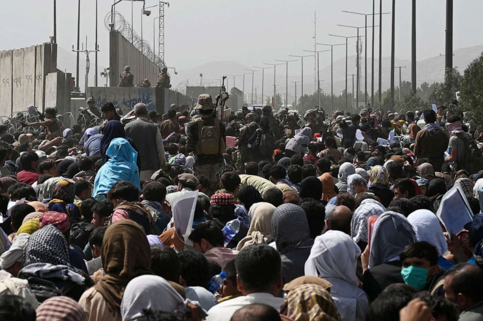 PHOTO: Afghans gather on a roadside near the military part of the airport in Kabul on August 20, 2021, hoping to flee from the country after the Taliban's military takeover of Afghanistan.