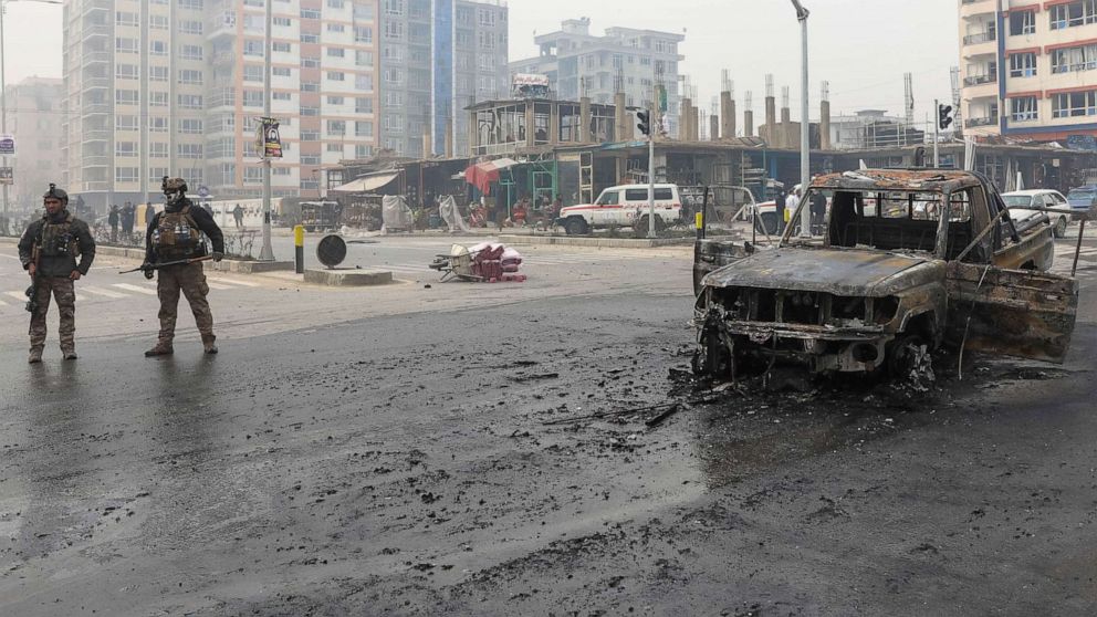 PHOTO: A charred vehicle sits in the road as Afghan security forces inspect the site of a bomb explosion in Kabul, Afghanistan, Dec. 20, 2020.