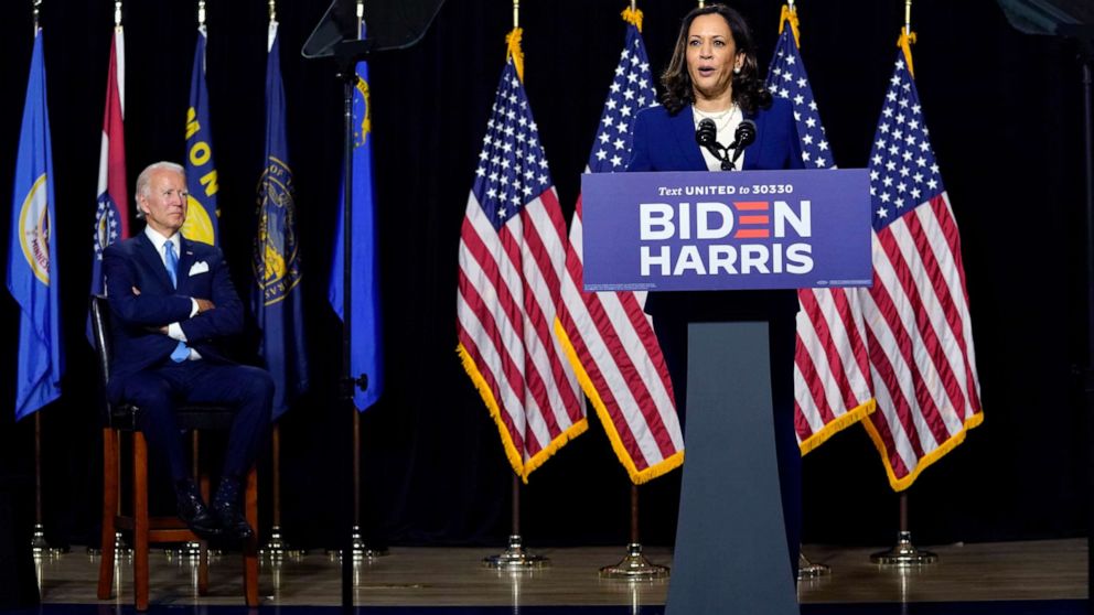 PHOTO: Democratic presidential candidate former Vice President Joe Biden listens as his running mate Sen. Kamala Harris speaks during a campaign event at Alexis Dupont High School in Wilmington, Del., Aug. 12, 2020.