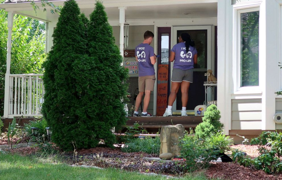PHOTO: Ben Kennedy, left, and Alyssa Winters go door-to-door to speak with prospective voters about a proposed amendment to the Kansas constitution that would allow legislators to further restrict or ban abortion, July 8, 2022, in Olathe, Kan.