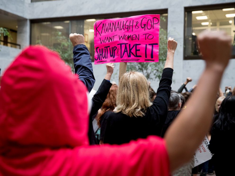 A protester of Supreme Court nominee Brett Kavanaugh wears a costume from the show The Handmaids Tale, and another protester holds up a sign that reads Kavanaugh and GOP Want Women to Shut Up and Take It in Washington, Monday, Sept. 24, 2018.