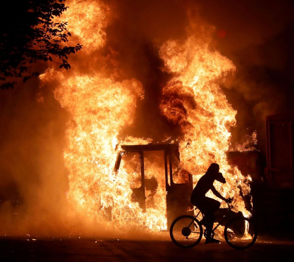 PHOTO: A man on a bike rides past a city truck on fire outside the Kenosha County Courthouse in Kenosha, Wis., Aug 23, 2020, during protests following the police shooting of Jacob Blake.