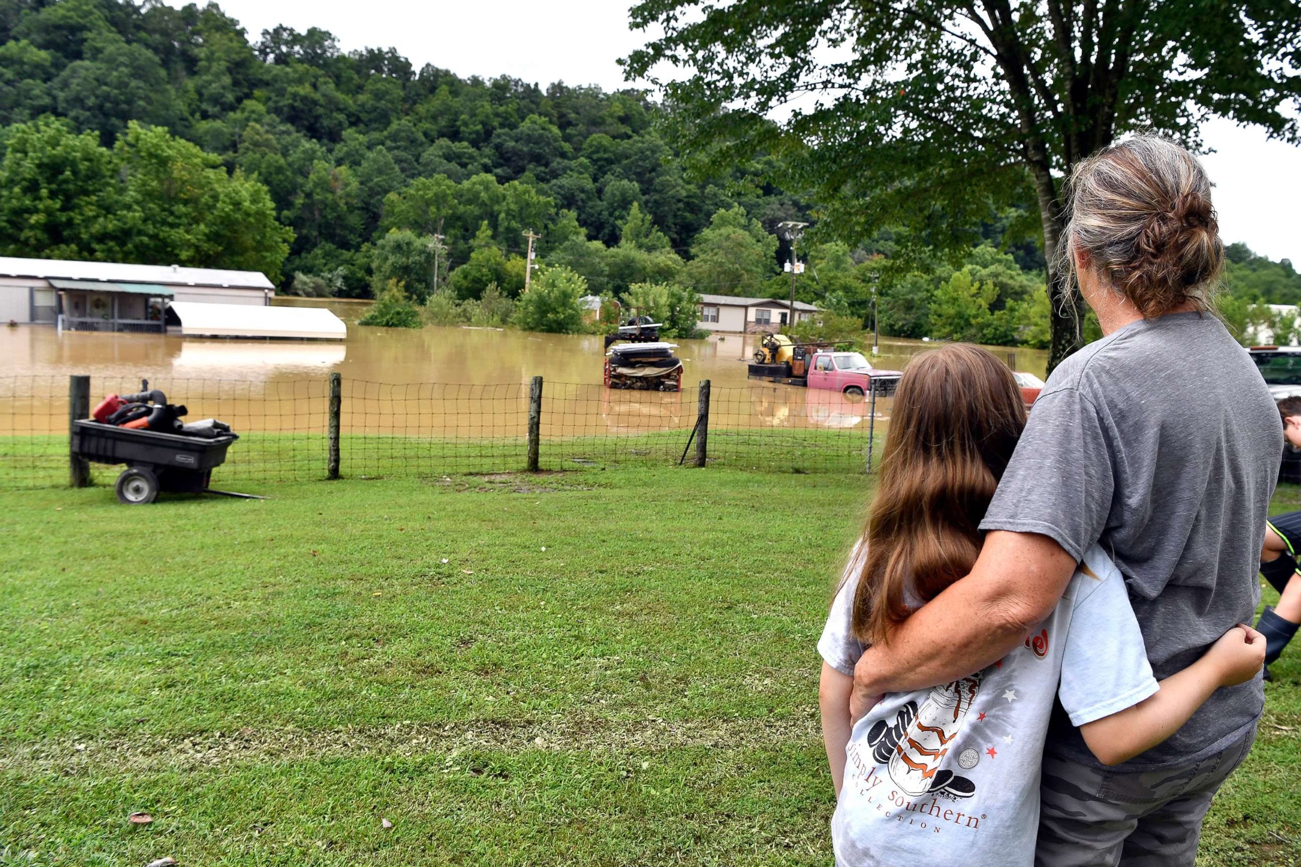 PHOTO: Bonnie Combs hugs her 10-year-old granddaughter Adelynn Bowling, as she watches  her property become covered by the North Fork of the Kentucky River in Jackson, Ky., July 28, 2022. 