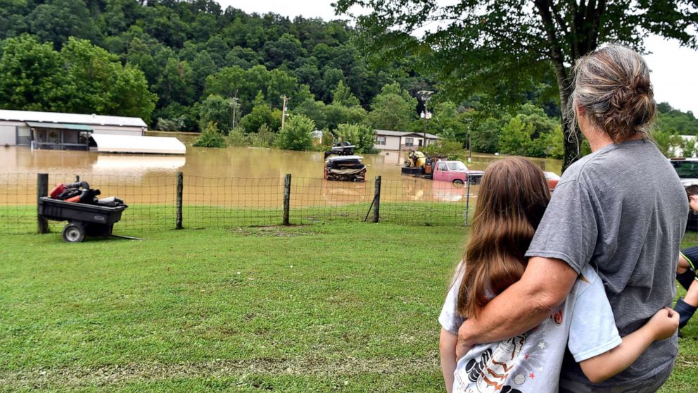 PHOTO: Bonnie Combs hugs her 10-year-old granddaughter Adelynn Bowling, as she watches  her property become covered by the North Fork of the Kentucky River in Jackson, Ky., July 28, 2022. 