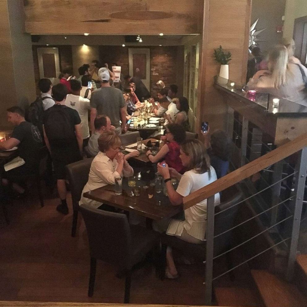 PHOTO: Activists chant slogans as they interrupt U.S. Homeland Security Secretary Kirstjen Nielsen's (top R) dinner at a restaurant in Washington, D.C., June 19, 2018, in this photo obtained from social media.