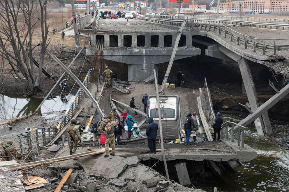 PHOTO: People cross a destroyed bridge as they evacuate the city of Irpin, northwest of Kyiv, during a heavy shelling and bombing, March 5, 2022.