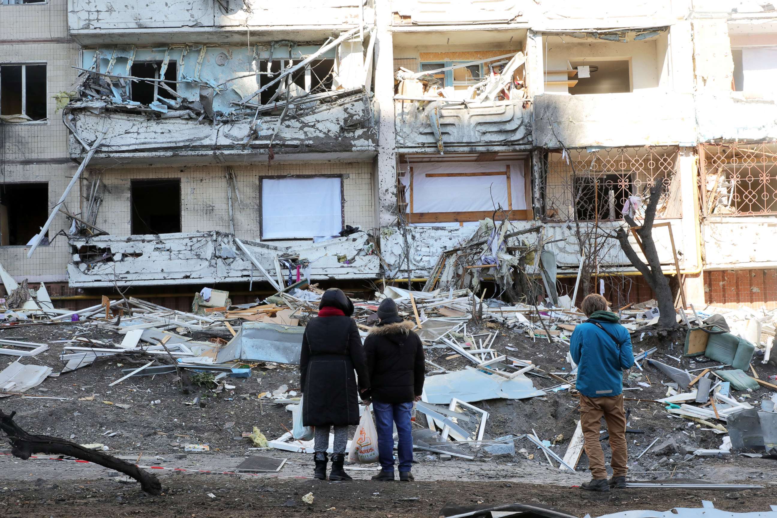 PHOTO: People look at damage caused by a shelling that took place early in the morning to a ten-story apartment block in the Podilskyi district of Kyiv, Ukraine, on March 15, 2022.
