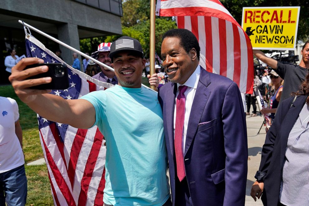 PHOTO: In this July 13, 2021 file photo, radio talk show host Larry Elder, center, poses for selfies with supporters during a campaign stop in Norwalk, Calif.