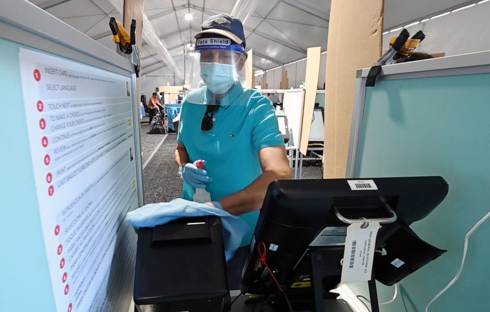 PHOTO: A poll worker sanitizes a voting booth between voters inside a tent at a shopping center on the first day of in-person early voting on Oct. 17, 2020, in Las Vegas.