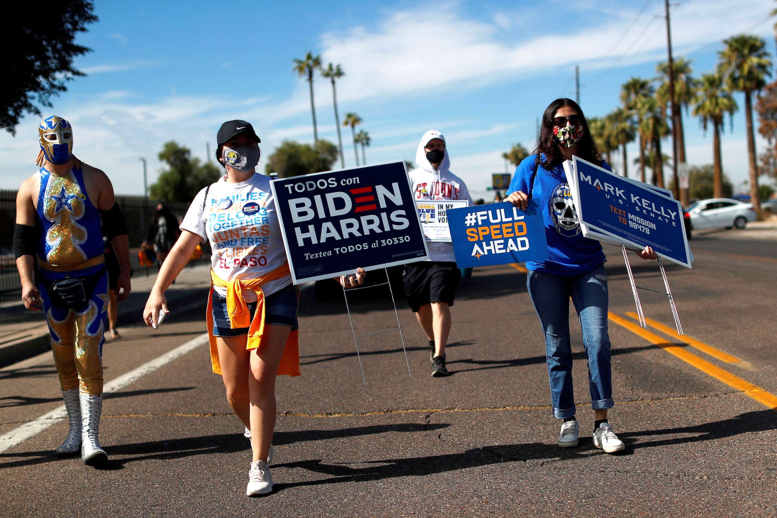 PHOTO: People carry posters in support of Democratic presidential nominee Joe Biden, vice presidential candidate Kamala Harris, and senate candidate Mark Kelly, during an event to promote the importance of the Latino vote in Phoenix, Oct. 31, 2020. 