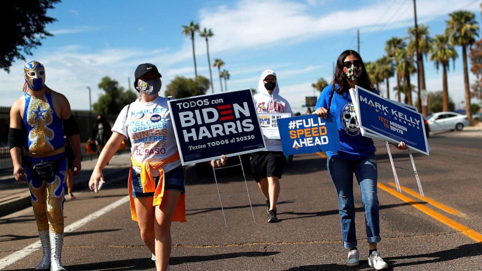 PHOTO: People carry posters in support of Democratic presidential nominee Joe Biden, vice presidential candidate Kamala Harris, and senate candidate Mark Kelly, during an event to promote the importance of the Latino vote in Phoenix, Oct. 31, 2020. 