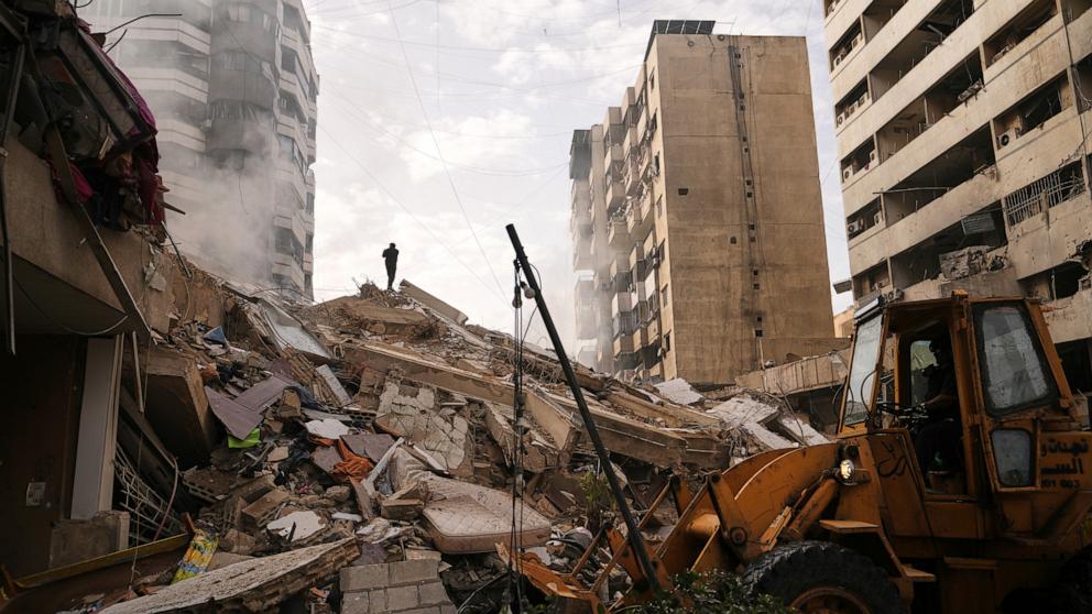 PHOTO: A man stands atop the rubble of a building destroyed in an Israeli airstrike as a bulldozer clears debris in Dahiyeh, Beirut's southern suburbs, Lebanon, March 14, 2026.