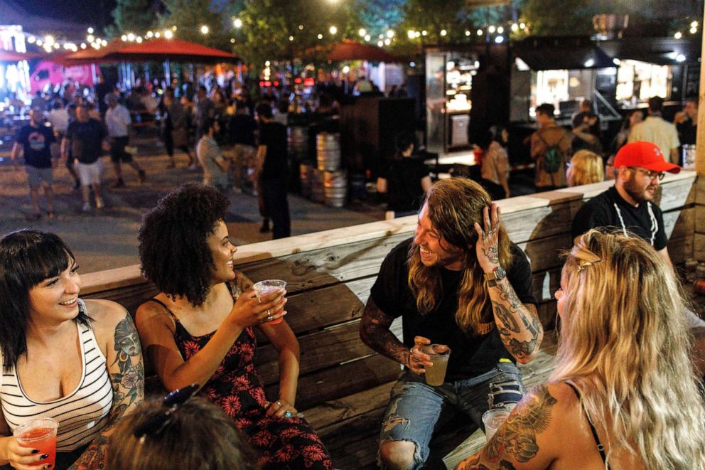 PHOTO: People enjoy socializing on the porch of Land-Grant Brewing Company with outdoor seating and activities setup at the establishment located in the Franklinton Arts District of Columbus, Ohio, June 2, 2021.