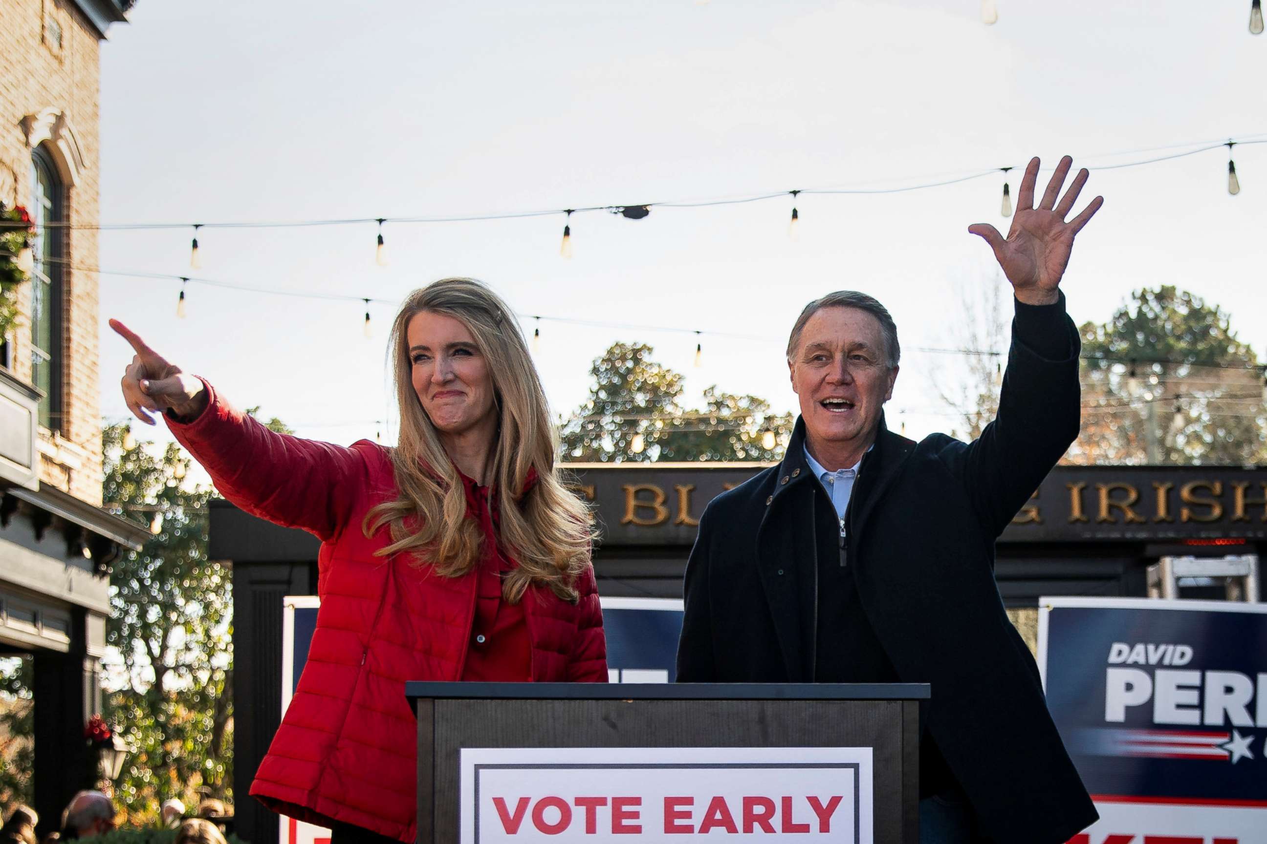 PHOTO: Sen. Kelly Loeffler and Sen. David Perdue wave during a campaign event at the Olde Blind Dog Irish Pub, in Milton, Ga., Dec. 21, 2020.