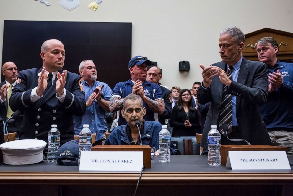 PHOTO:  Michael O'Connelll, left, John Feal, center, and Jon Stewart, right, applaud Luis Alvarez during a House Judiciary Committee hearing on reauthorization of the September 11th Victim Compensation Fund.