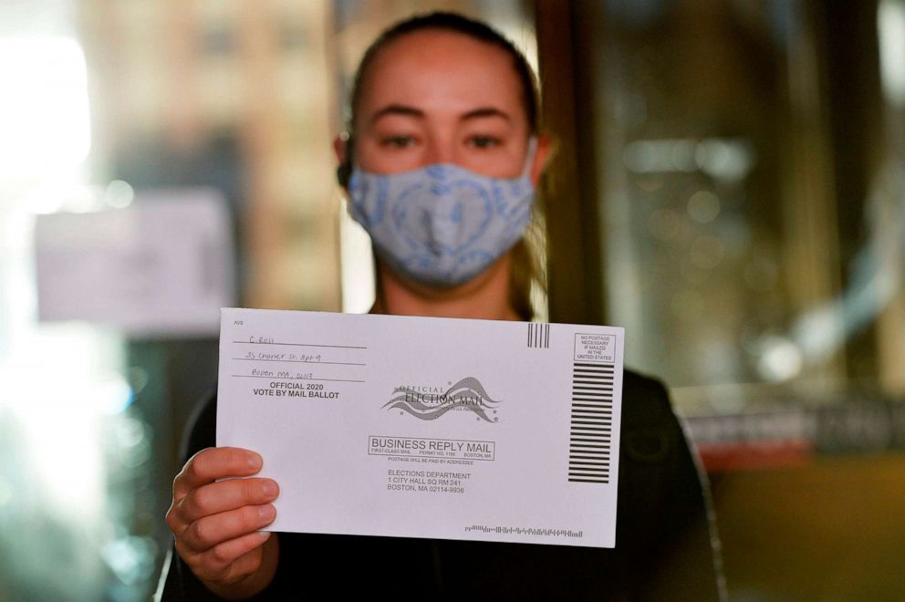 PHOTO: A woman holds up a mail-in ballot before dropping it off at Boston City Hall during the Massachusetts State Primary, Sept. 1, 2020, in Boston.