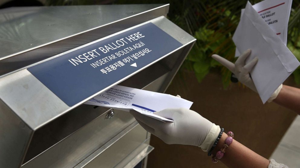 PHOTO: In this July 7, 2020, file photo a woman wearing gloves drops off a mail-in ballot at a drop box in Hackensack, N.J.
