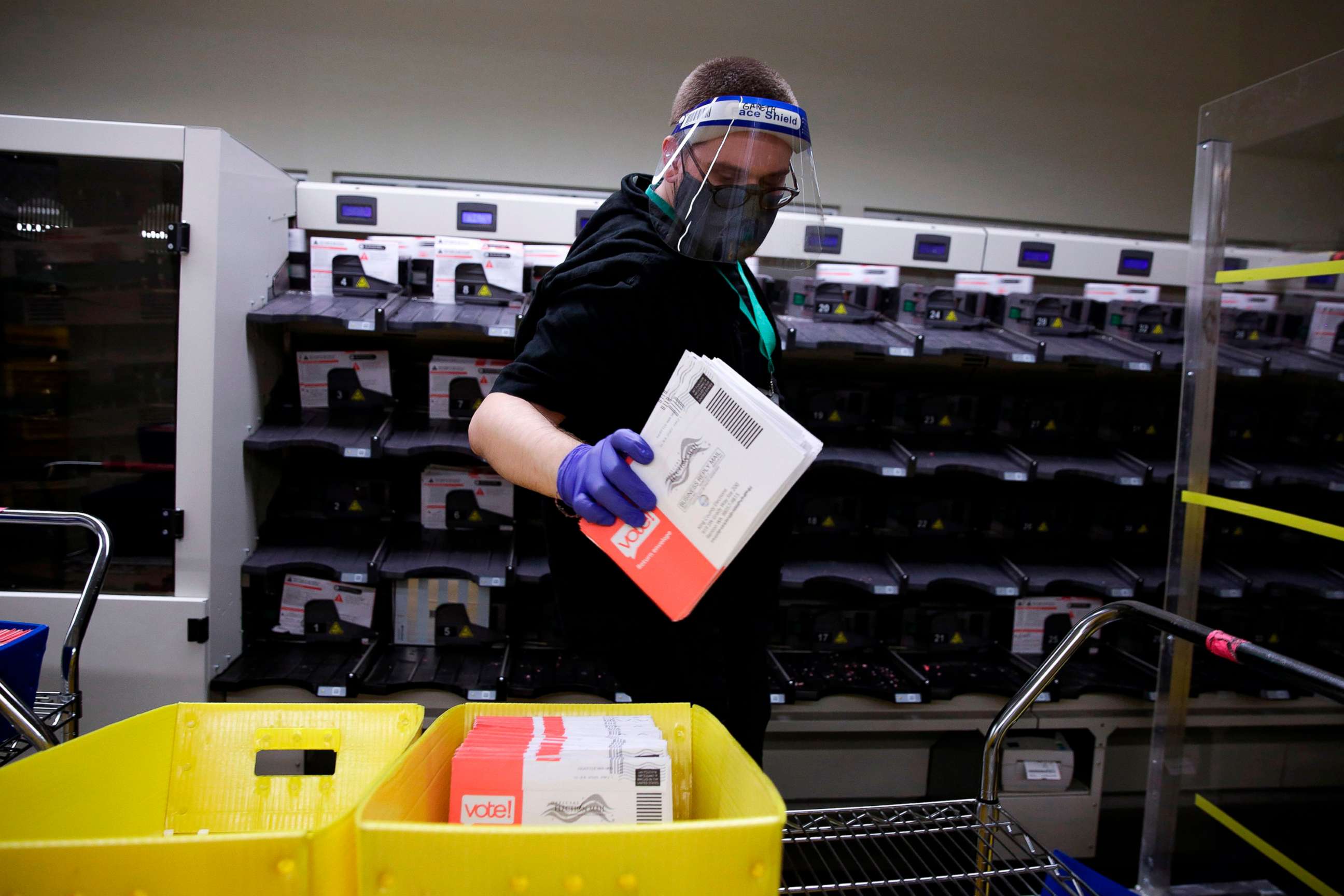 PHOTO: An election worker removes ballots from a sorting machine as vote-by-mail ballots for the Aug. 4, Washington state primary are processed at King County Elections in Renton, Wash., on Aug. 3, 2020.