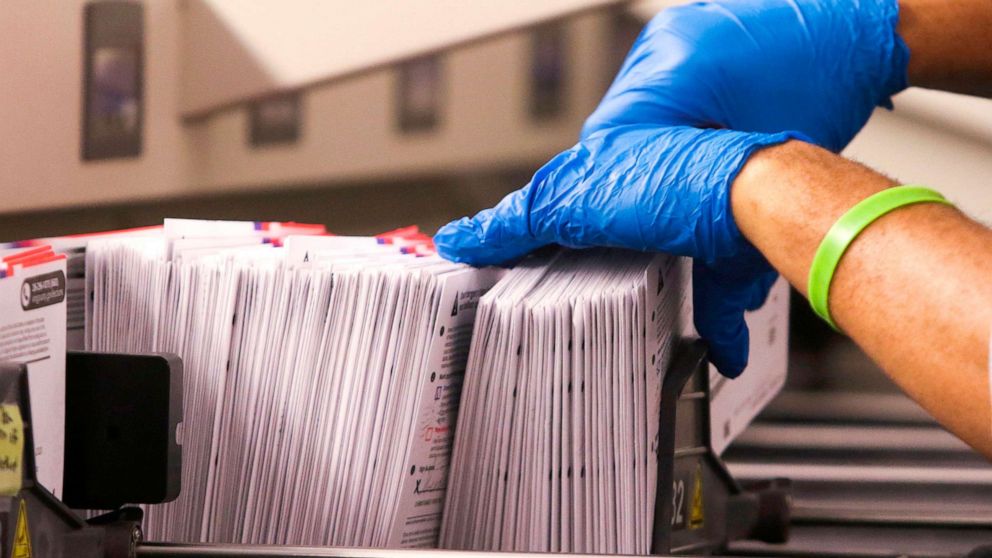 PHOTO: An election worker handles vote-by-mail ballots coming out of a sorting machine for the presidential primary at King County Elections in Renton, Washington,  March 10, 2020.