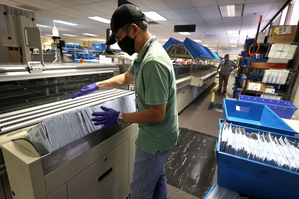 PHOTO: George Hiu places mail-in ballots into a sorting machine at the Santa Clara County registrar of voters office on Oct. 13, 2020, in San Jose, Calif.