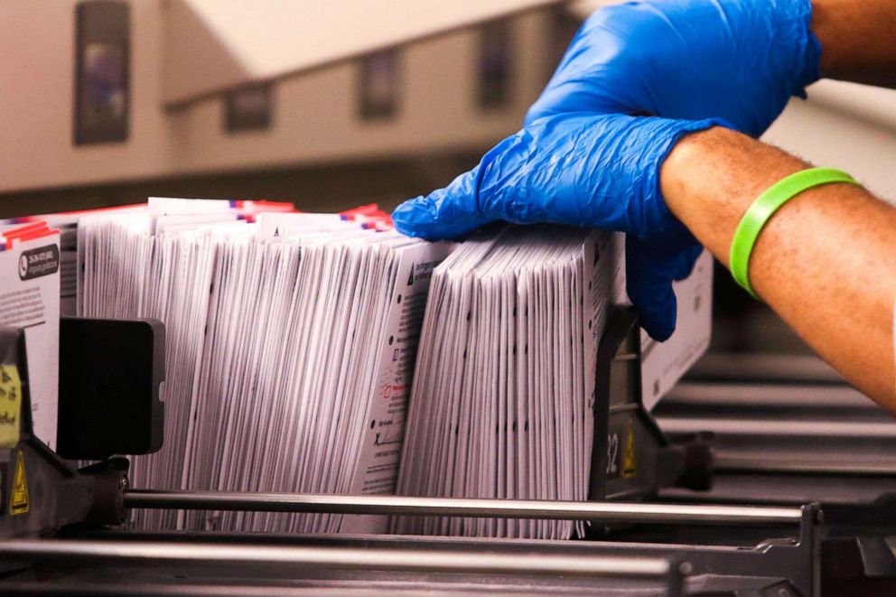 PHOTO: An election worker handles vote-by-mail ballots coming out of a sorting machine for the presidential primary at King County Elections in Renton, Washington, March 10, 2020.