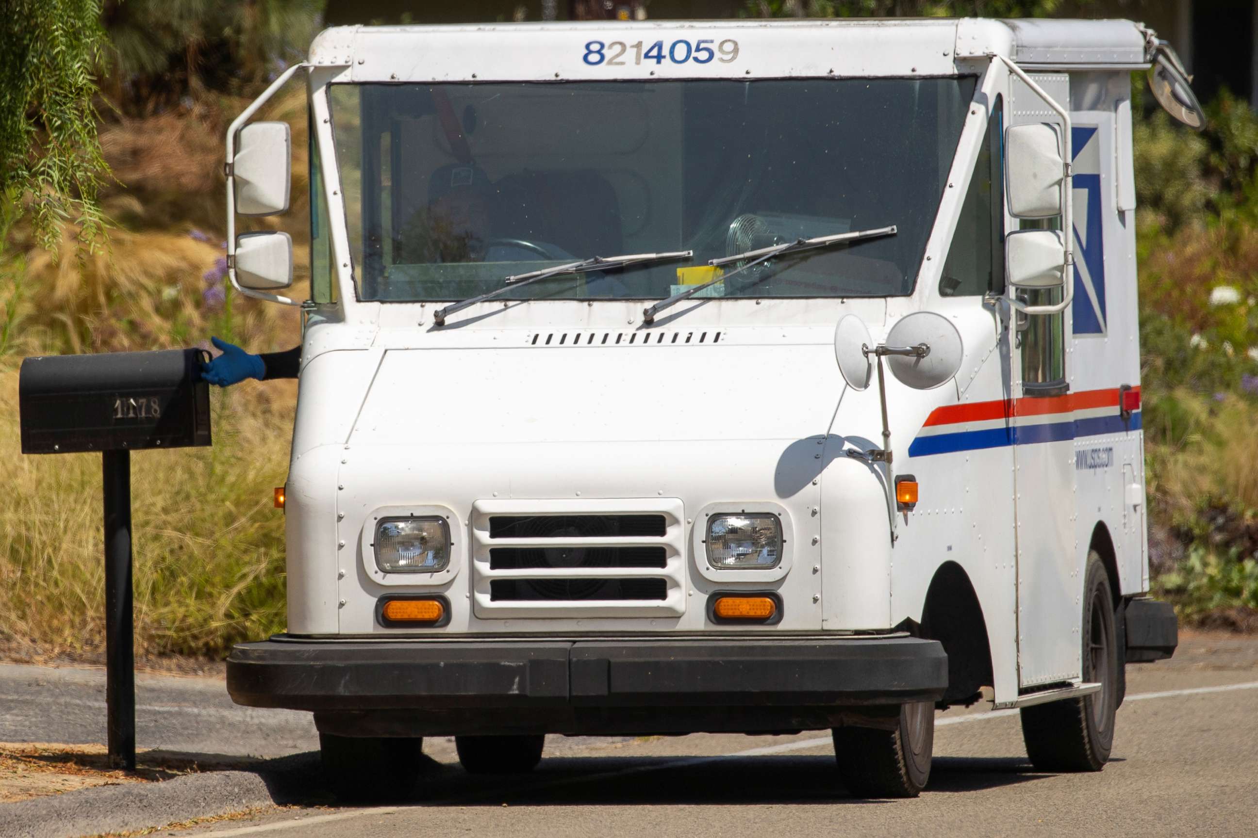 PHOTO: A U.S. postal service worker delivers mail during the outbreak of COVID-19 in Encinitas, Calif., July 30, 2020.