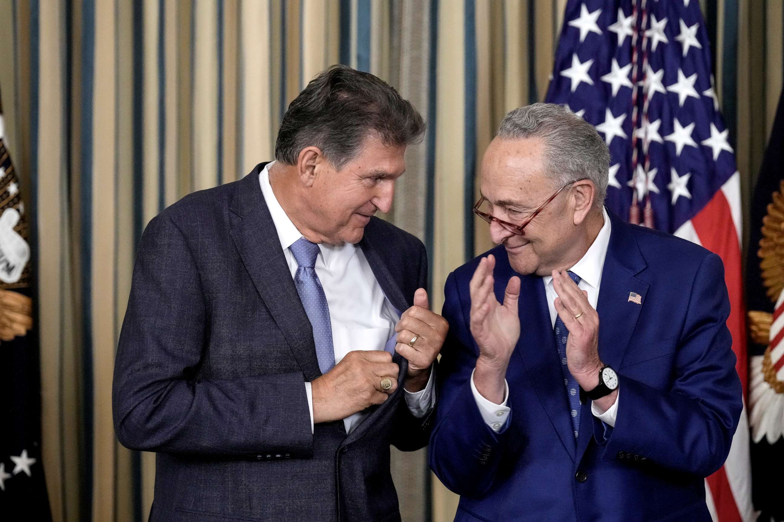 PHOTO: Sen. Joe Manchin looks to Senate Majority Leader Chuck Schumer after U.S. President Joe Biden signs The Inflation Reduction Act in the State Dining Room of the White House August 16, 2022 in Washington, DC.