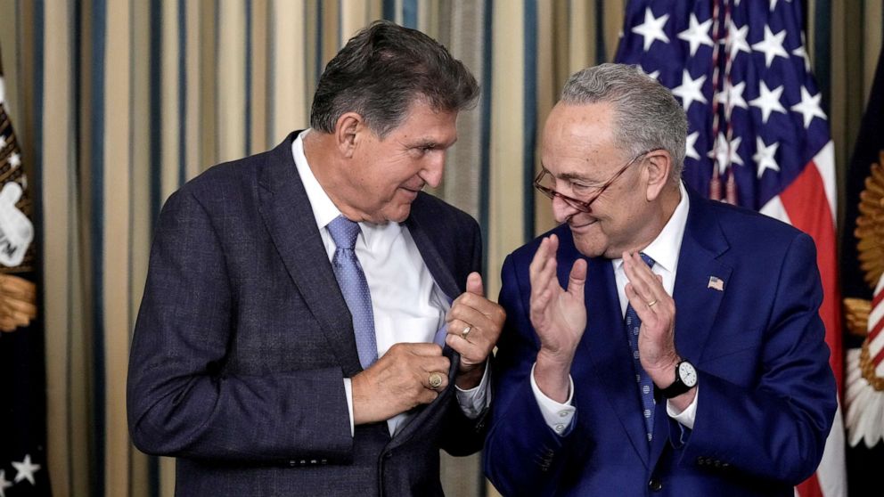 PHOTO: Sen. Joe Manchin looks to Senate Majority Leader Chuck Schumer after U.S. President Joe Biden signs The Inflation Reduction Act in the State Dining Room of the White House August 16, 2022 in Washington, DC.