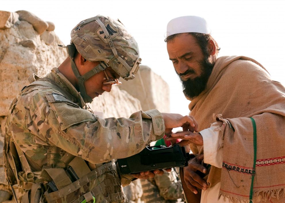 PHOTO:Army Pfc. Mark Domingo, takes an Afghan male's fingerprints in the village of Dande Fariqan, Nov. 5, 2012.