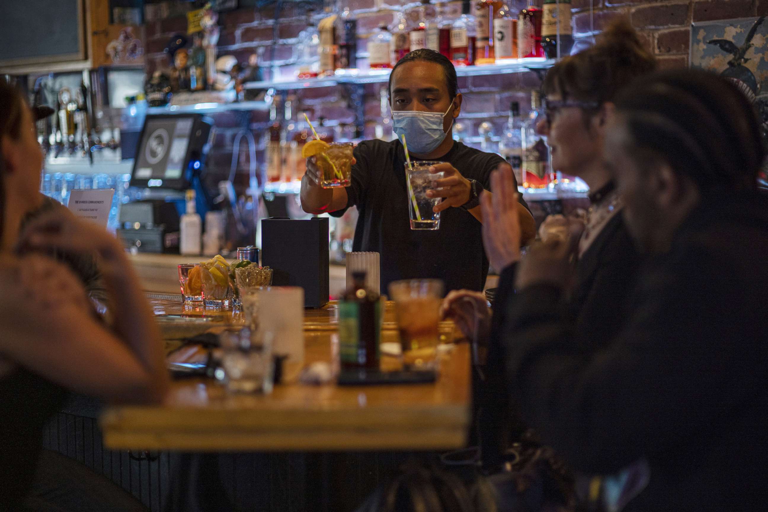 PHOTO: A bartender wearing a protective mask serves drinks in a bar in San Francisco, May 6, 2021. 