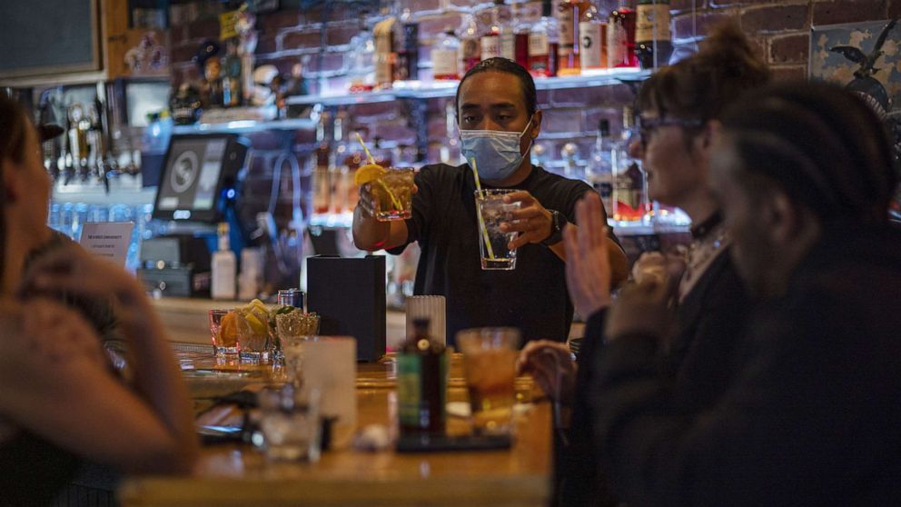 PHOTO: A bartender wearing a protective mask serves drinks in a bar in San Francisco, May 6, 2021. 