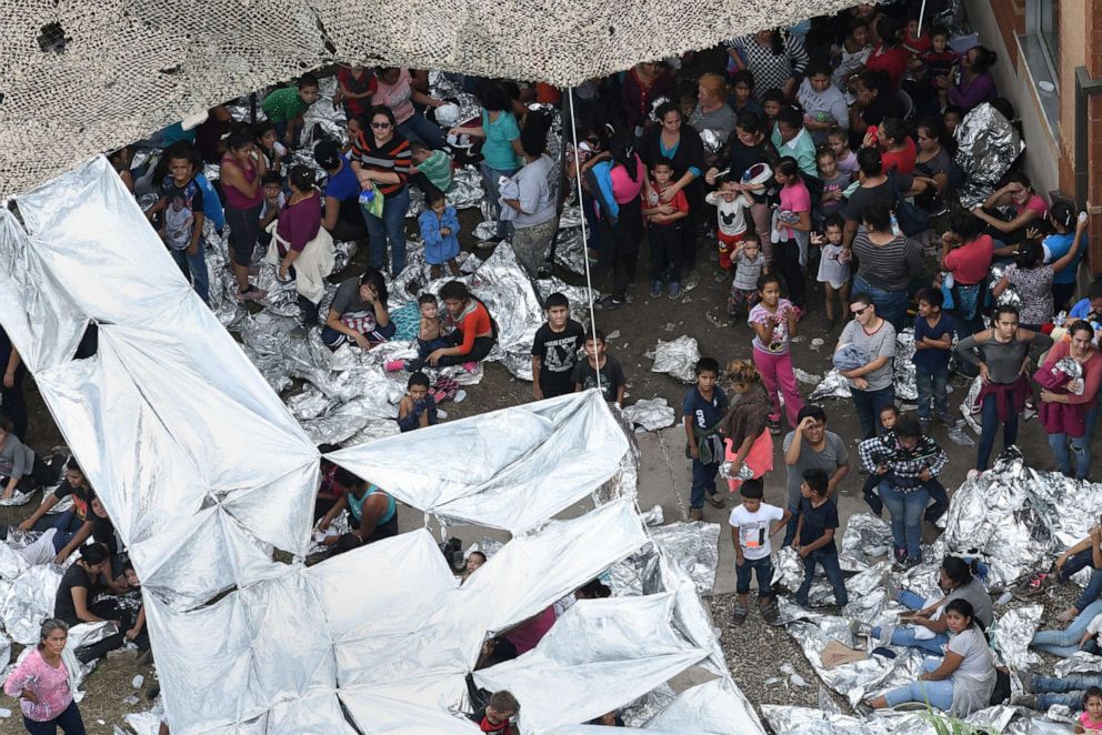 PHOTO: Migrants wait outside a makeshift encampment at the U.S. Border Patrol facility in McAllen, located close to the Central Processing Center where a suspected flu outbreak has prompted officials to stop processing, in McAllen, Texas, May 15, 2019.