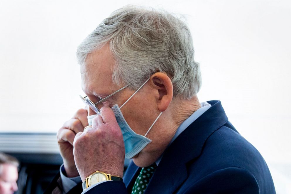 PHOTO: Senate Majority Leader Mitch McConnell takes off a face mask to give brief remarks to members of the news media at the Senate carriage entrance on Capitol Hill in Washington, D.C., April 20, 2020.