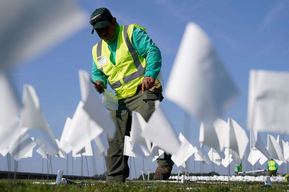 PHOTO: A worker plants white flags as part of artist Suzanne Brennan Firstenberg's temporary art installation, &quot;In America: Remember,&quot; in remembrance of Americans who have died of COVID-19, on the National Mall in Washington, Sept. 15, 2021.