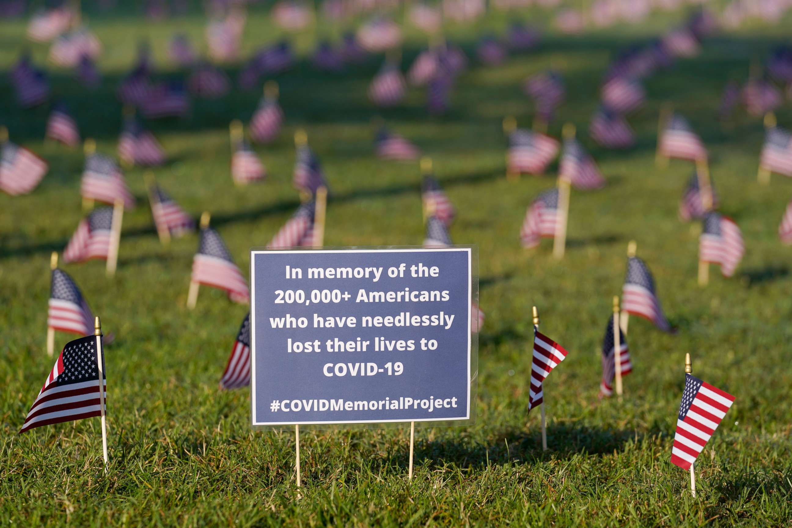 PHOTO: Activists from the COVID Memorial Project mark the deaths of 200,000 lives lost in the U.S. to COVID-19 after placing thousands of small American flags places on the grounds of the National Mall in Washington, Sept. 22, 2020.