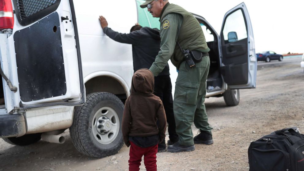 A child watches as a U.S. Border Patrol agent searches a fellow Central American migrant after they crossed the border from Mexico on Feb. 01, 2019, in El Paso, Texas.