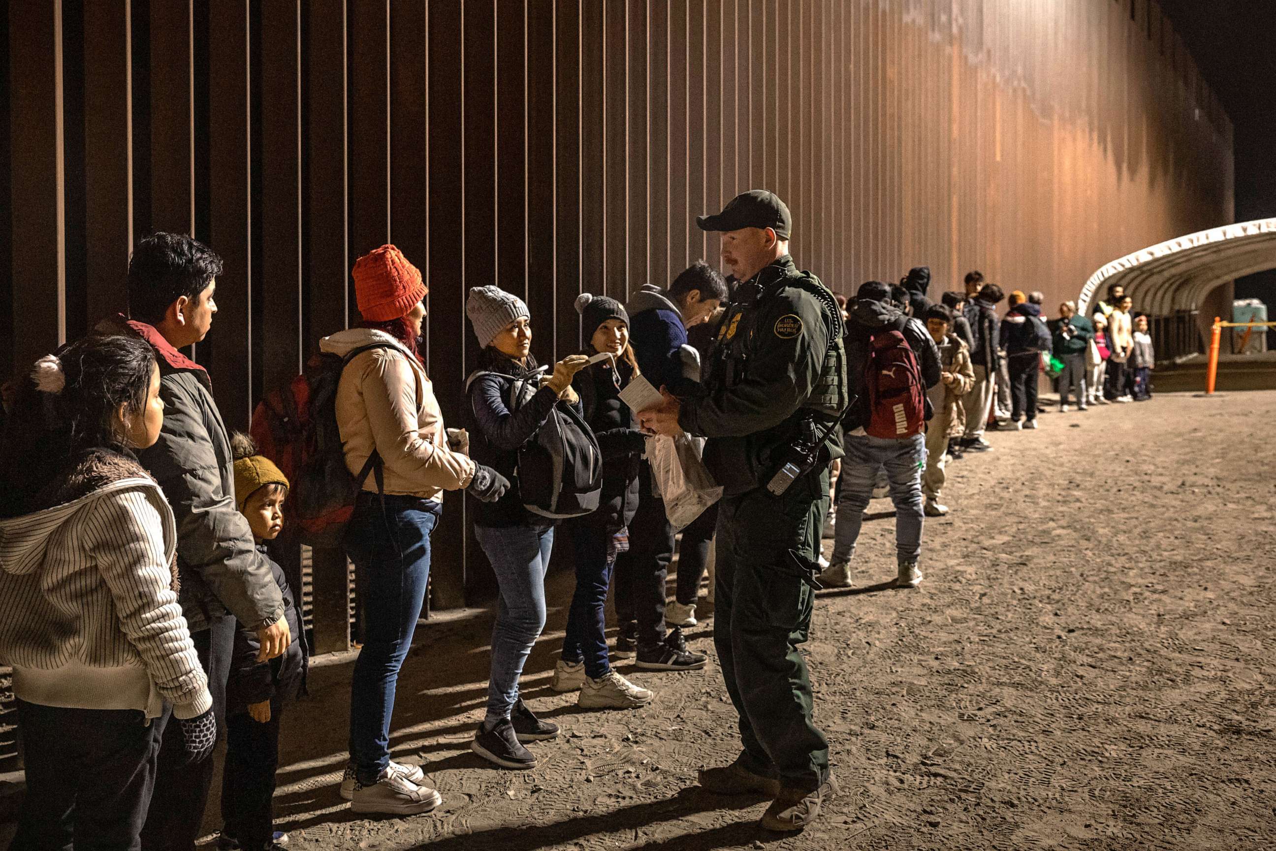 PHOTO: In this Dec. 30, 2022, file photo, a U.S. Border Patrol agent checks for identification of immigrants as they wait to be processed by the U.S. Border Patrol in Yuma, Ariz.