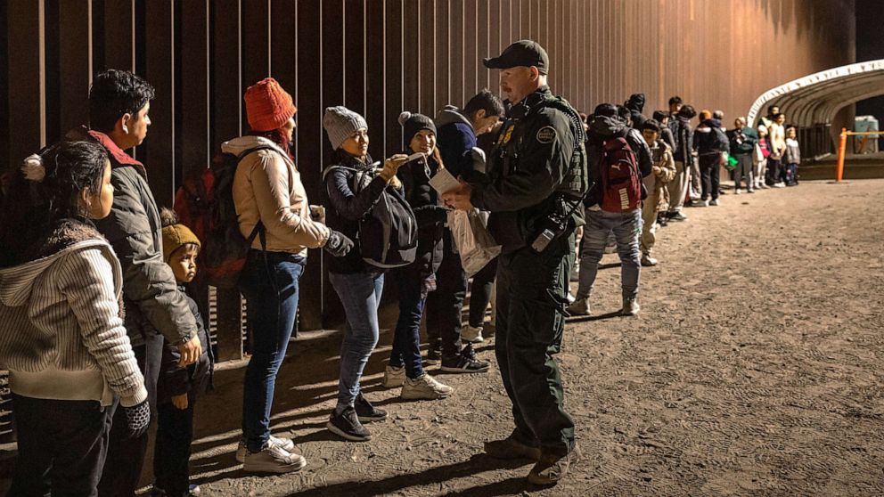 PHOTO: In this Dec. 30, 2022, file photo, a U.S. Border Patrol agent checks for identification of immigrants as they wait to be processed by the U.S. Border Patrol in Yuma, Ariz.