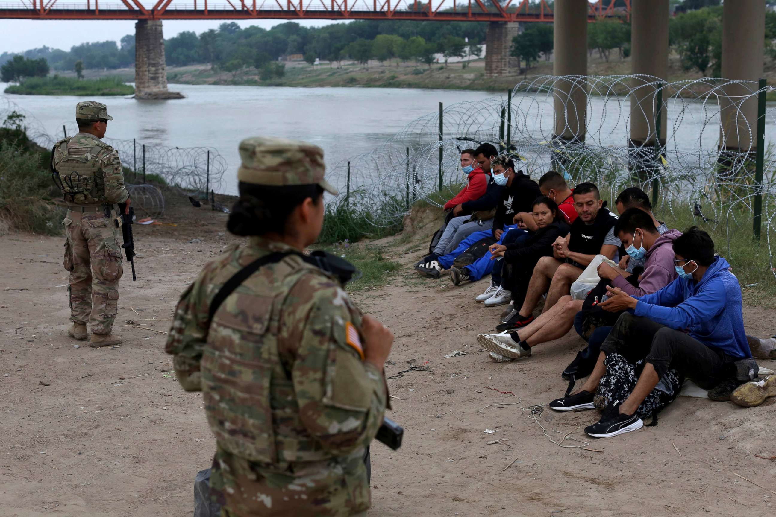 PHOTO: Migrants who had crossed the Rio Grande river into the U.S. are under custody of National Guard members as they await the arrival of U.S. Border Patrol agents in Eagle Pass, Texas, on May 20, 2022.