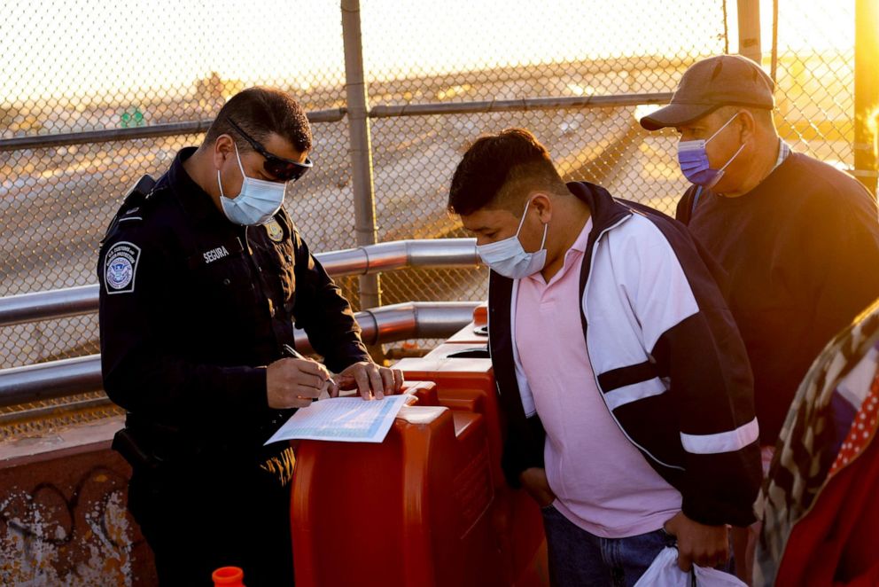 PHOTO: Asylum-seeking migrants are assisted by a U.S. Customs and Border Protection agent at the Paso del Norte International Bridge to attend a court hearing for asylum seekers, in Ciudad Juarez, Mexico, March 15, 2022.