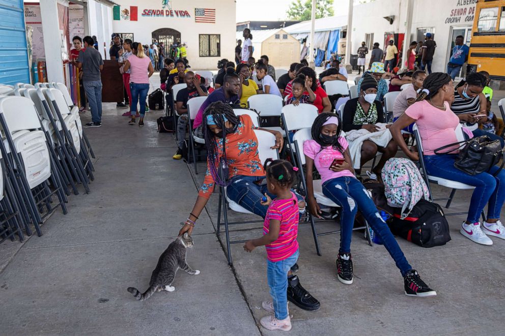 PHOTO: In this August 30, 2022 file photo, two migrants interact with a stray cat as they wait with other migrants at the Senda de Vida shelter in Reynosa, Mexico.
