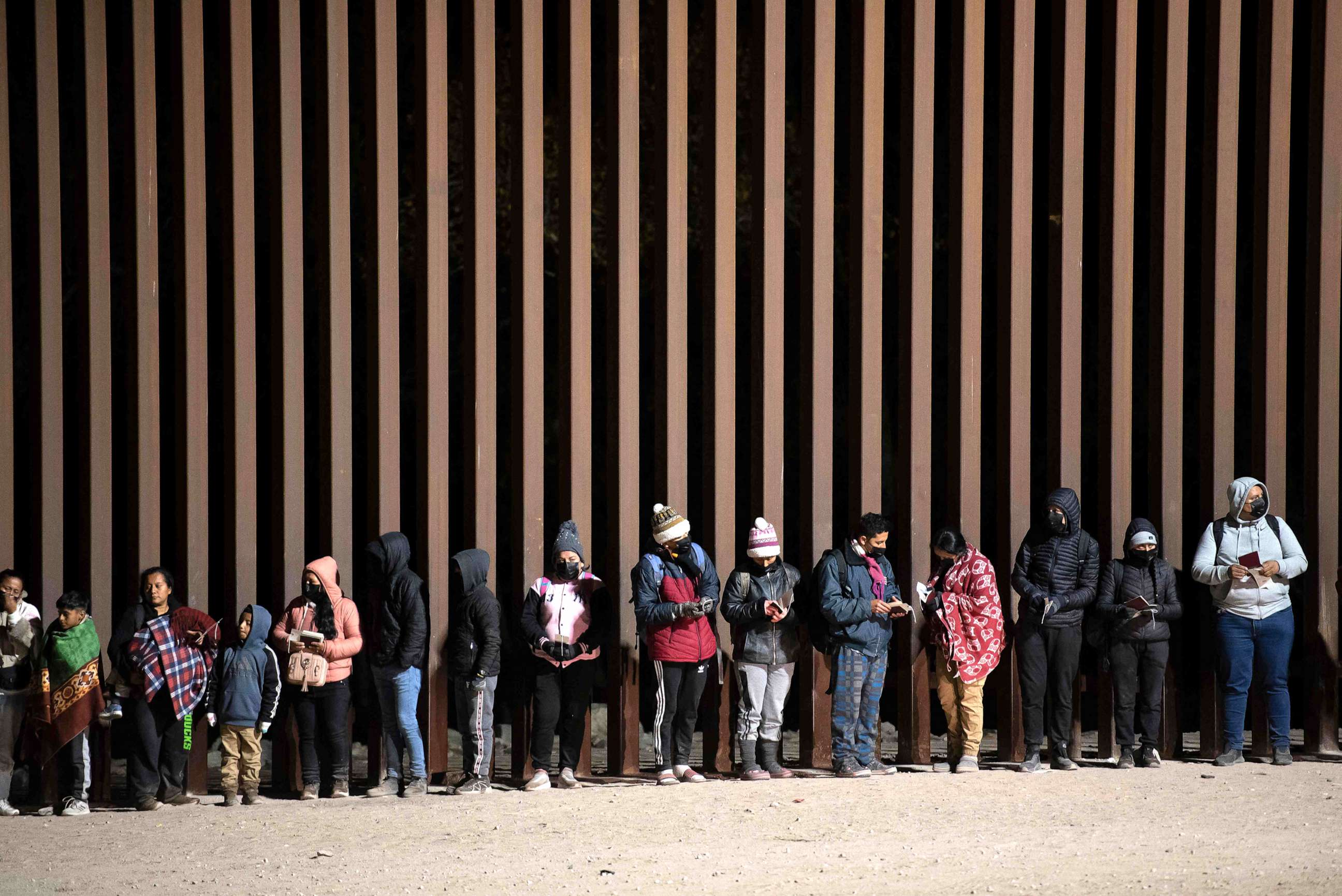 PHOTO: In this Dec. 26, 2022, file photo, asylum-seekers line up to be processed by US Customs and Border Patrol agents at a gap in the US-Mexico border fence near Somerton, Ariz.