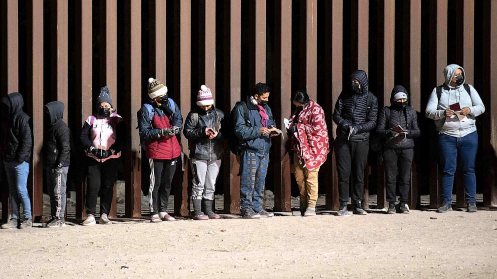 PHOTO: In this Dec. 26, 2022, file photo, asylum-seekers line up to be processed by US Customs and Border Patrol agents at a gap in the US-Mexico border fence near Somerton, Ariz.