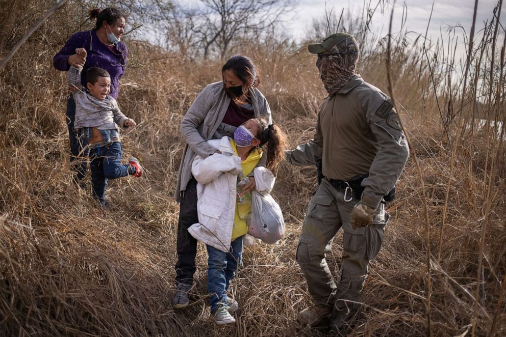 PHOTO: Two children and their mothers are escorted out of the brush by a Texas State Trooper after crossing the Rio Grande river into the United States from Mexico on a raft in Penitas, Texas, March 9, 2021.