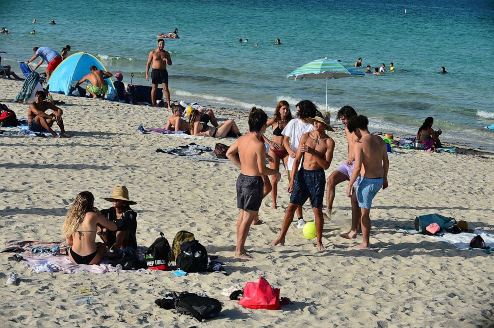 PHOTO: Beach-goers are seen on the beach after a mandate to wear face masks in public spaces went into effect on June 30, 2020, in Miami Beach, Fla.