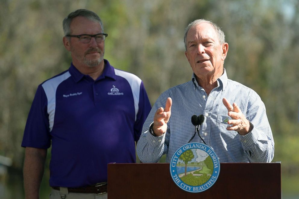 PHOTO: Former New York City Mayor Michael Bloomberg, right, answers a question from a reporter as Orlando Mayor Buddy Dyer listens after touring an Orlando Utilities Commission facility, Feb. 8, 2019, in Orlando, Fla.