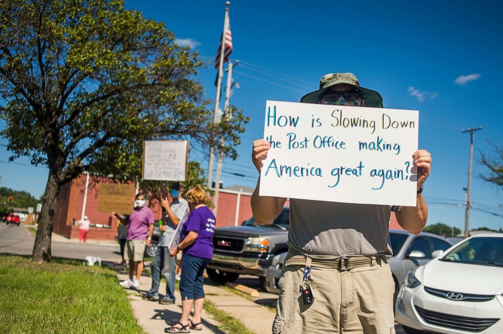 PHOTO: Eric Severson holds a sign as a few dozen people gather in front of the United States Post Office to protest recent changes to the U.S. Postal Service under new Postmaster General Louis DeJoy, Aug. 11, 2020 in Midland, Mich.